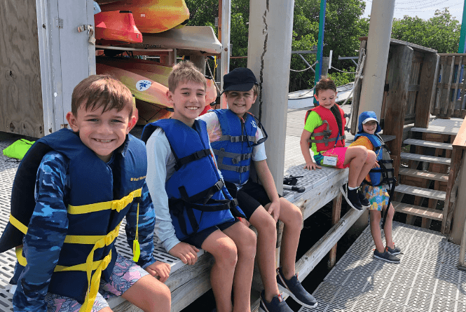Children in life jackets seated at the Environmental Learning Center canoe dock